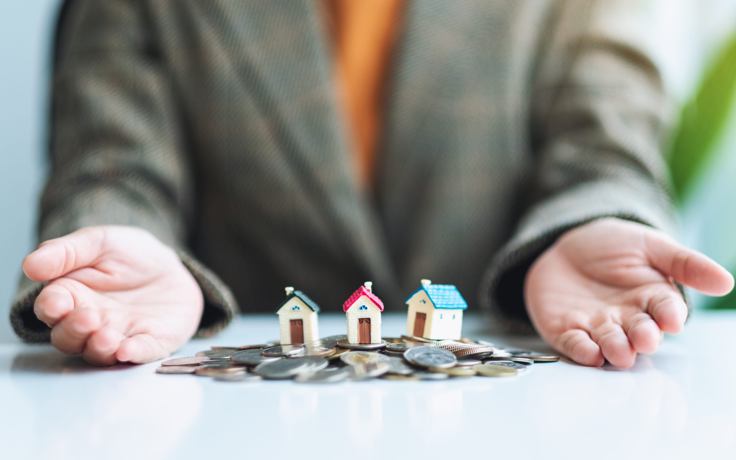 Closeup image of people showing house models on pile of coins fo